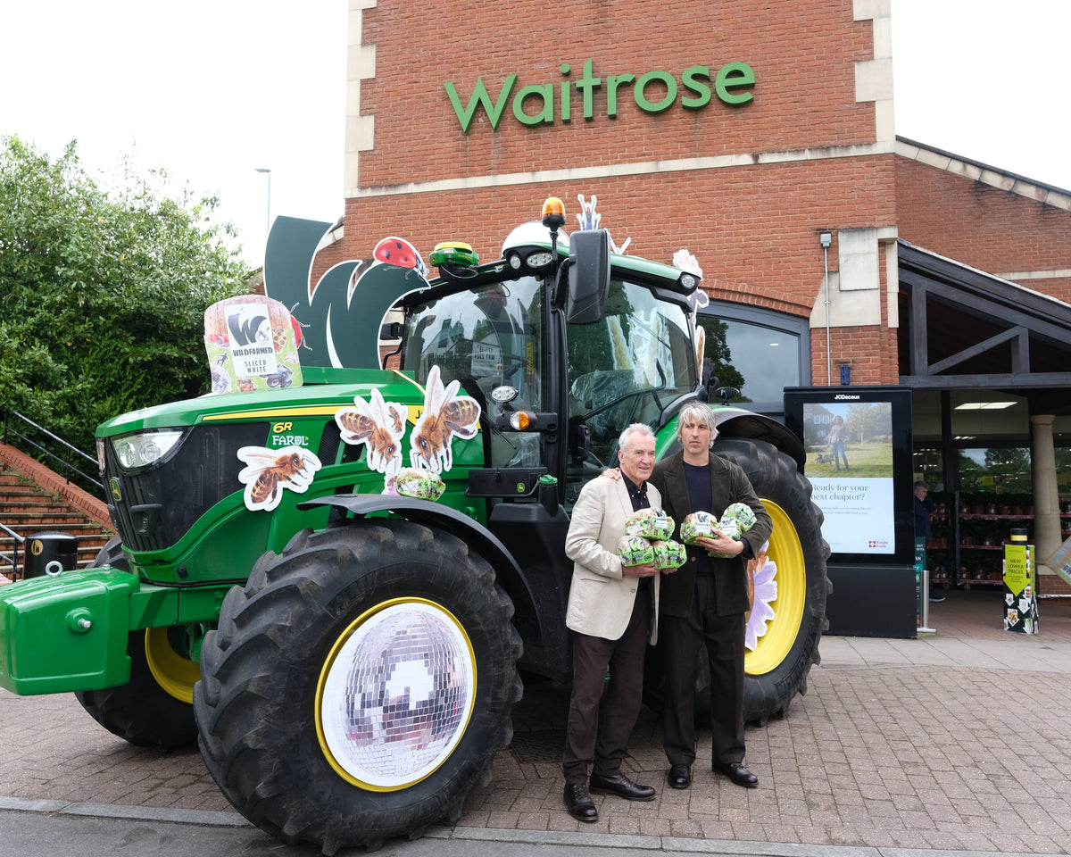 George & Larry Lamb standing next to a large green tractor outside a Waitrose store